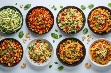 A vibrant and diverse spread of plant-based dishes featuring colorful ingredients like zucchini noodles, roasted red peppers, chickpeas, and cashews, representing recipes from the "Almost Vegan Cookbook."