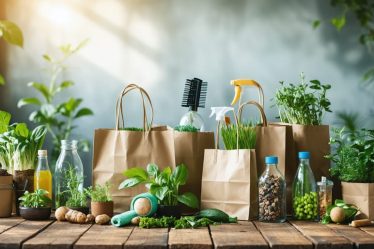 A collection of eco-friendly items including colorful reusable shopping bags, glass containers for food storage, and homemade natural cleaning supplies on a wooden table.