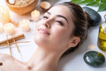 A radiant woman glowing with vitality amidst elements symbolizing holistic skincare, including organic botanicals, acupuncture needles, LED light therapy, and natural oils.