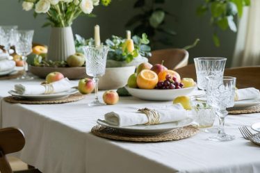 A calming dining table setting with warm lighting, simple table arrangements, fresh flowers, and seasonal fruits, evoking a sense of peace and mindfulness.