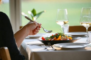 A person thoughtfully preparing to eat at a beautifully set table, embodying the practice of mindful eating with elements of calmness and focus around them.