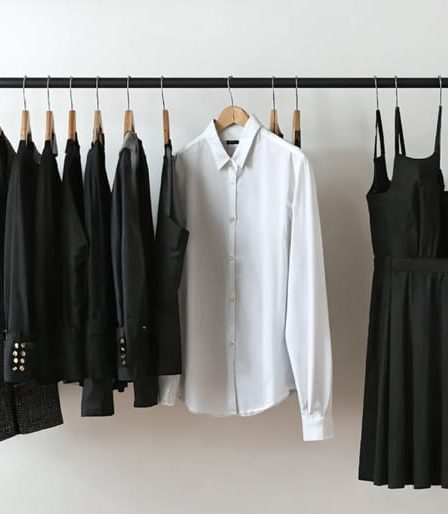 A conceptual image depicting essential wardrobe items like a blazer, white button-down shirt, dark jeans, and a little black dress, symbolizing the creation of a personal and quality wardrobe.