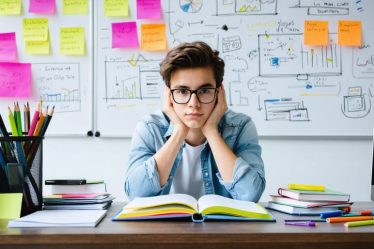 Determined student studying entrepreneurship with a mix of digital and traditional materials, including Quizlet flashcards, in preparation for an FBLA competition.