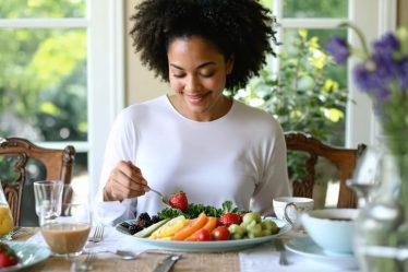 A person sitting at a dining table, mindfully enjoying a colorful meal in a peaceful environment, symbolizing the balance of mindful and intuitive eating practices.