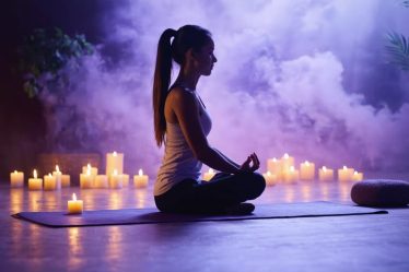 Person practicing gentle yoga stretches in a softly lit room with meditation cushions and flameless candles, embodying the peace of a mindful movement session before bed.