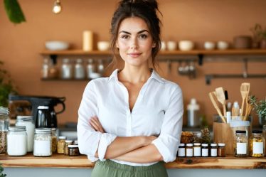 Female beauty entrepreneur working in her kitchen, surrounded by skincare ingredients and product materials, symbolizing the journey from passion to business success.