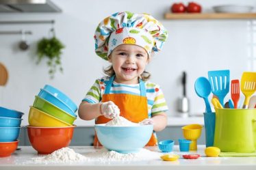 Six-year-old child wearing a colorful chef's hat and apron, happily measuring flour into a bowl with bright, child-friendly kitchen tools around.