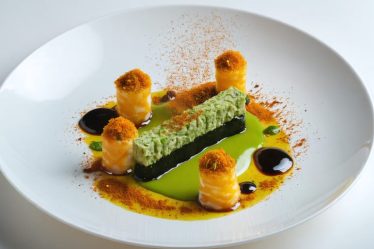 An elegantly plated gourmet dish showcasing a fusion of global flavors, featuring French presentation with Asian and exotic influences like wasabi-infused sauce, saffron, and za'atar.