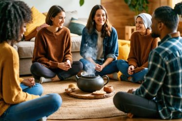 Diverse group of individuals sitting in a cozy living room, engaging in an authentic and meaningful conversation, with shared snacks and warm lighting highlighting their connectedness.