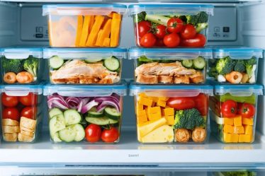 Open fridge filled with a week's worth of neatly organized, labeled meal prep containers showcasing a variety of colorful, portioned meals.