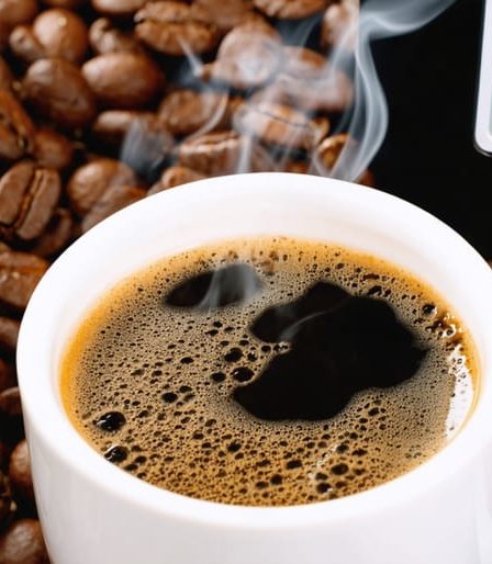 A steaming cup of coffee with a digital thermometer reading 200°F, surrounded by coffee beans, illustrating the importance of precise brewing temperature for optimal flavor extraction.