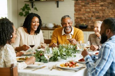 A multi-generational family engaging in conversation around a dinner table, enjoying a meal together without electronic devices, illustrating the theme of strengthening family bonds through improved communication.