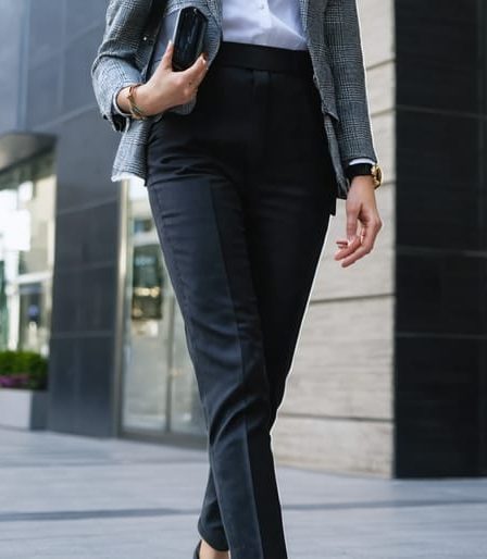 A fashionable individual confidently walking in a cityscape, showcasing wearable tech accessories like a luxury smartwatch and sleek smart jewelry integrated into a stylish business outfit.