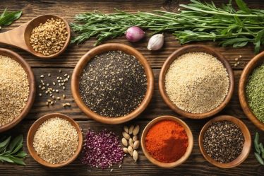 A visually appealing display of ancient grains including quinoa, amaranth, teff, and spelt arranged in rustic wooden bowls, complemented by fresh herbs and vintage kitchen utensils, illustrating their nutritional richness and versatility.