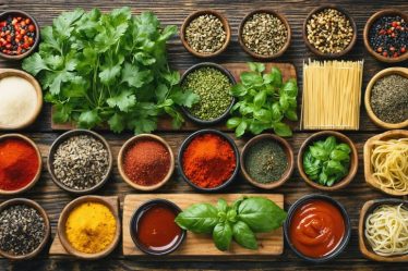 A colorful assortment of street food ingredients from around the world, including fresh herbs, spices, noodles, and sauces, displayed on a wooden table.