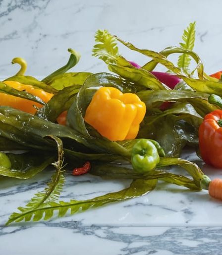 A vibrant and fresh arrangement of kelp intertwined with colorful vegetables on a marble surface, highlighting its nutrient-rich properties and culinary versatility.
