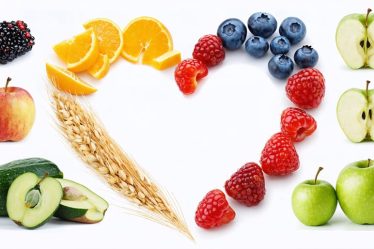 A heart-shaped arrangement featuring various plant-based, fiber-rich foods, highlighting the connection between fiber and overall wellness, including apples, berries, quinoa, oats, and green vegetables.